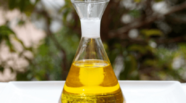 Aceitera con aceite de oliva sobre mesa blanca y al aire libre