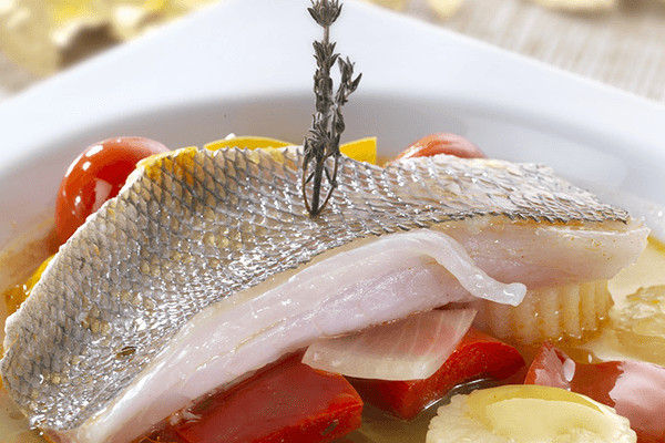 Detalle de besugo estofado con pimientos, tomate y cebolla