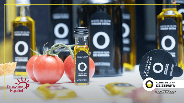 Mesa blanca con botellas y envases de aceite de oliva y tomates. 