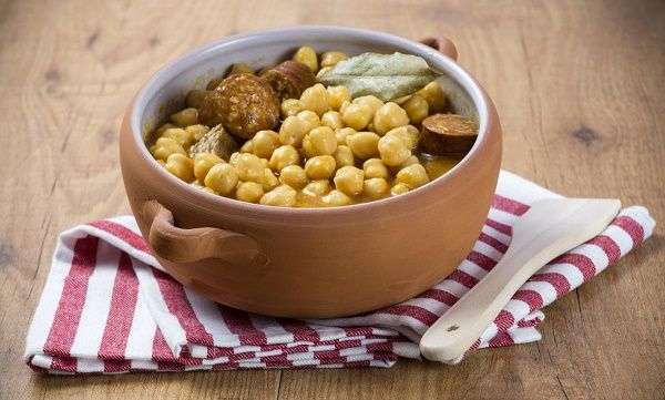 Cocido en cazo sobre servilleta y cuchara de madera