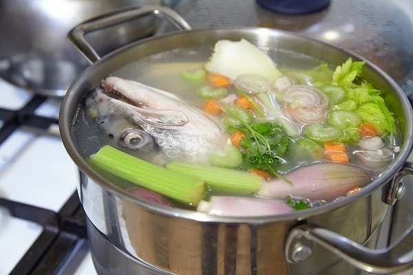 cabeza, espinas y piel de pescado hirviendo con dados de verdura