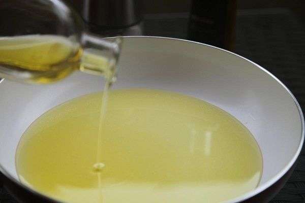 Aceite de oliva cayendo desde botella a sartén 