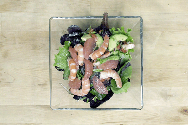 Cuenco con ensalada de gambas con aguacate y pomelo sobre madera