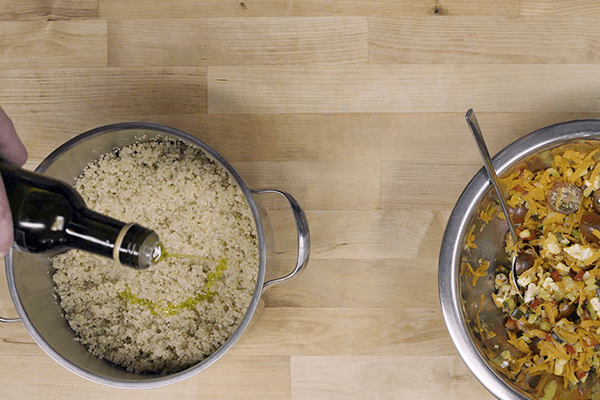 Recipiente con quinoa y recipiente con hortalizas sobre mesa de madera