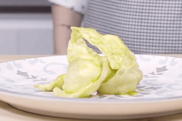 Fritos de queso en plato con grecas sobre mesa de madera. Al fondo, silueta de persona. 