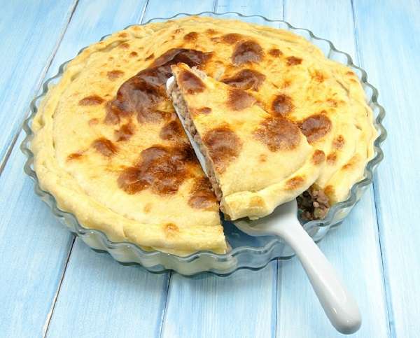 pastel de carne en recipiente tranparente sobre mesa de madera azul