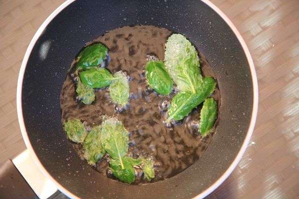 Hojas de menta friéndose en una sartén con aceite de oliva