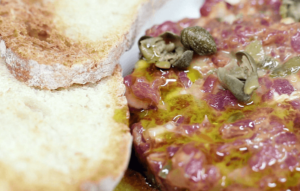Detalle de steak tartar con alcaparras, aceite de oliva y pan 