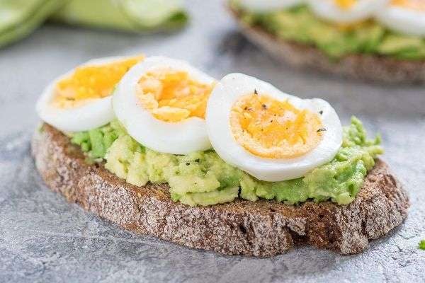 Tosta con aguacate y huevo duro laminado sobre pizarra