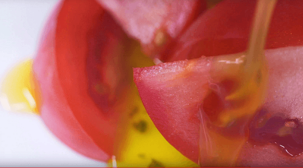 aceite de oliva cayendo sobre tomates en rodajas