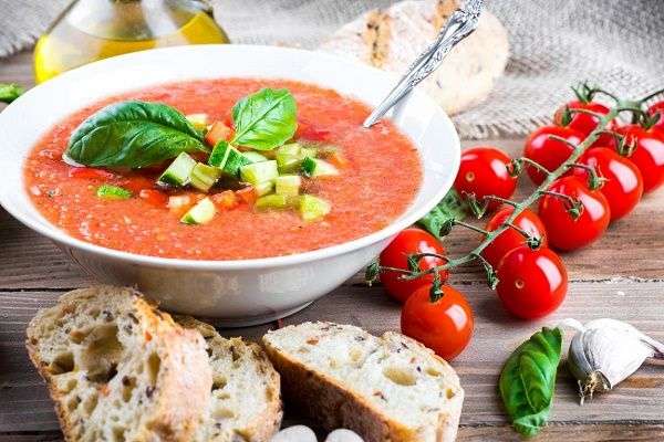 Plato de gazpacho con pepino y tomate y botella de aceite de oliva