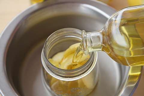 Verter el aceite de oliva con la cascara de limón en un tarro de cristal y poner al baño María