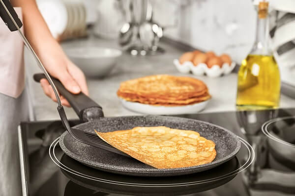 preparando en la cocina unas tortitas con aceite de oliva en la sarten caliente